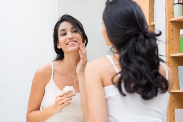 woman putting face moisturizer
