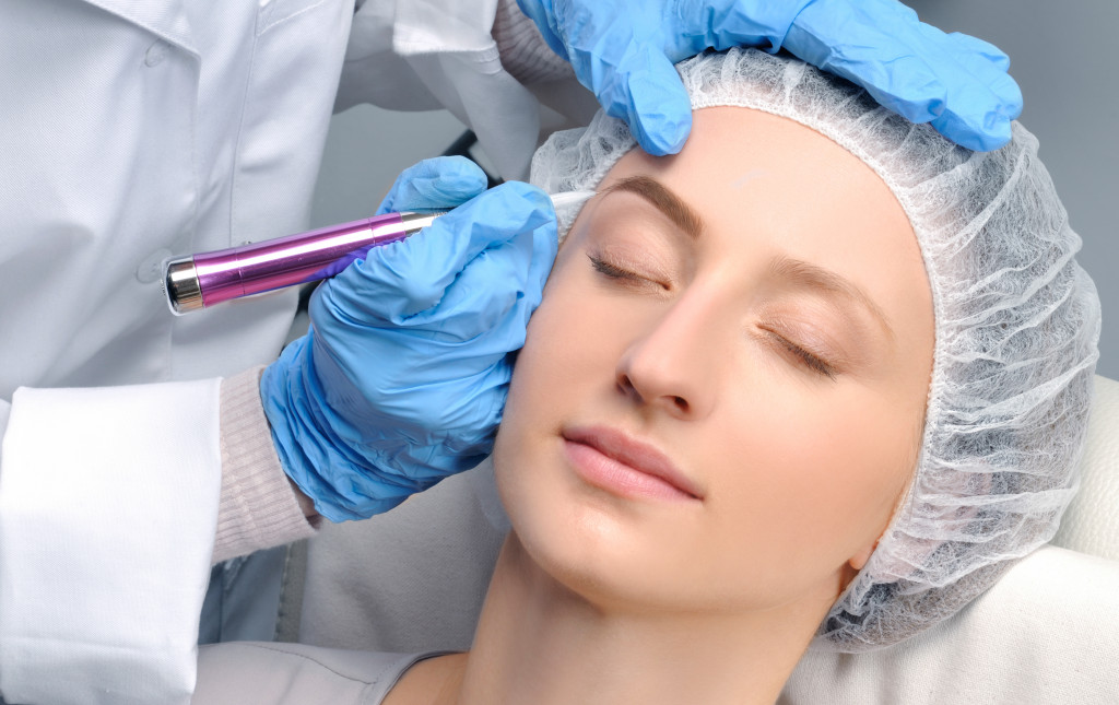 Cosmetologist making permanent makeup on woman