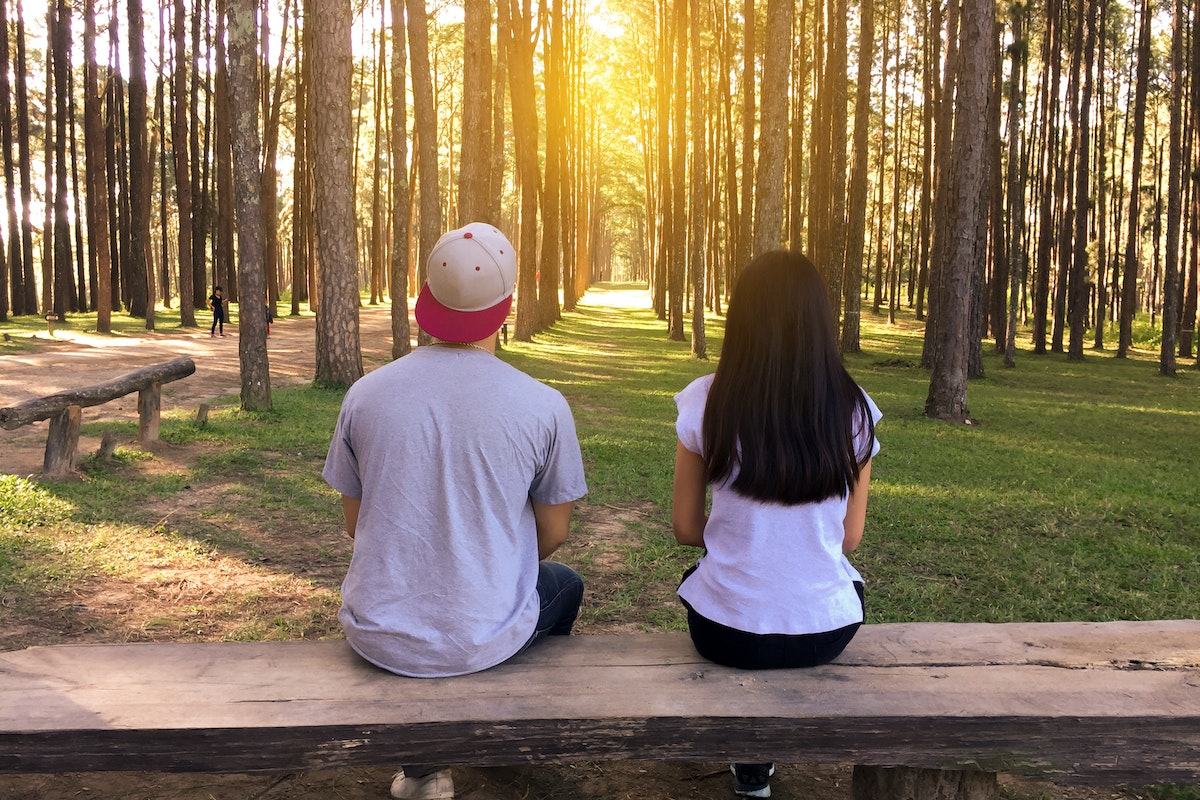 Man and Woman Sitting on Bench in Woods