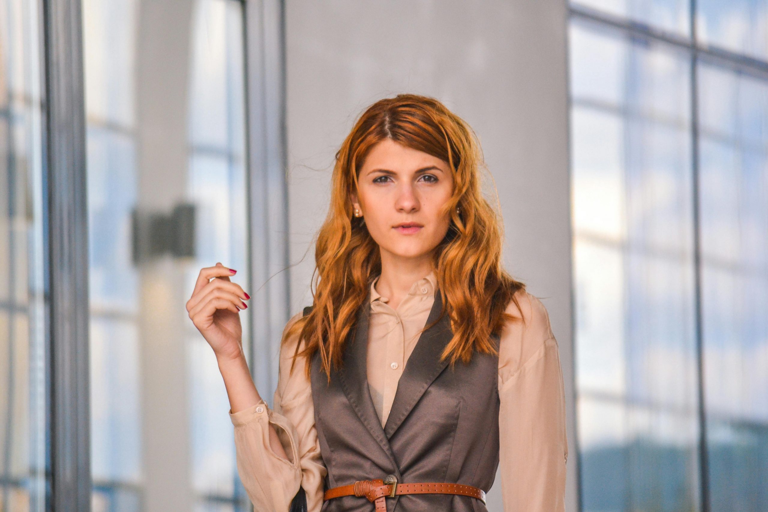woman wearing a peach loose blouse underneath a brown silk vest